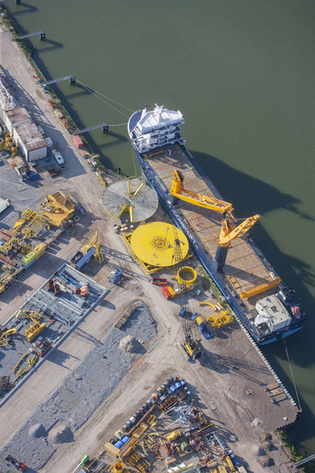 Rotterdam South Holland Netherlands 03 September 2014 Aerial view of Rotterdam Harbour with a cargo ship docked at the quay industrial machinery and yellow cranes. Rotterdam South Holland Netherlands 03 September 2014 Aerial view of Rotterdam Harbour with a cargo ship docked at the quay industrial machinery and yellow cranes.