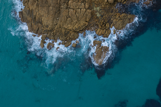 Aerial view of Conspicuous Cliff with rugged rock formations and turquoise ocean waves crashing against the shore in Nornalup Western Australia Australia. Aerial view of Conspicuous Cliff with rugged rock formations and turquoise ocean waves crashing against the shore in Nornalup Western Australia Australia.