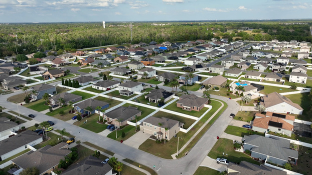 Aerial view of a suburban residential neighborhood with single family homes white fences paved streets and green lawns in Plant City Florida United States.