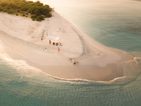 Aerial view of a pristine white sand beach kissed by the turquoise sea framed by lush green vegetation Dhidhdhoo Thiladhunmathi Atoll Maldives.