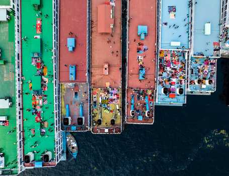 Aerial view of colorful passenger ferries docked at Sadarghat river port with many people on the decks along the Buriganga River in Dhaka Dhaka Division Bangladesh. Aerial view of colorful passenger ferries docked at Sadarghat river port with many people on the decks along the Buriganga River in Dhaka Dhaka Division Bangladesh.