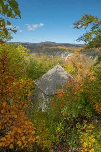 View of the stone tower of Castle Muran surrounded by vibrant autumn foliage and forested hills under a clear blue sky in Muran Banska Bystrica Region Slovakia. View of the stone tower of Castle Muran surrounded by vibrant autumn foliage and forested hills under a clear blue sky in Muran Banska Bystrica Region Slovakia.