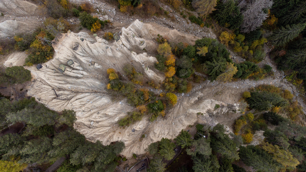 Aerial view of the Erdpyramiden Percha earth pyramids showcasing unique geological formations surrounded by autumn forests and rugged terrain in Plata Trentino Alto Adige Italy.