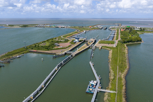 Aerial view of Lorentzsluizen lock complex showing the water gates green embankments and the expansive Wadden Sea under a cloudy sky Kornwerderzand Friesland Netherlands.