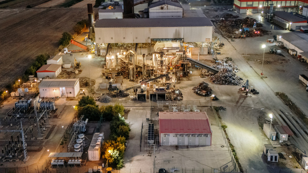 Aerial view of an industrial facility at night featuring illuminated factory buildings machinery scrap metal piles and power infrastructure in Sremska Mitrovica Vojvodina Serbia. Aerial view of an industrial facility at night featuring illuminated factory buildings machinery scrap metal piles and power infrastructure in Sremska Mitrovica Vojvodina Serbia.