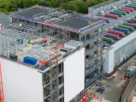 Aerial view of a large data center under construction featuring steel framework rooftop cooling units and site infrastructure in the United Kingdom.