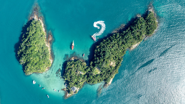 Aerial view of Blue Lagoon with lush green islands turquoise waters and small boats anchored in Angra dos Reis Rio de Janeiro Brazil.