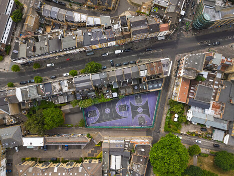 Aerial view of the purple basketball court in Shoreditch surrounded by dense urban buildings narrow streets and green trees in London England United Kingdom. Aerial view of the purple basketball court in Shoreditch surrounded by dense urban buildings narrow streets and green trees in London England United Kingdom.
