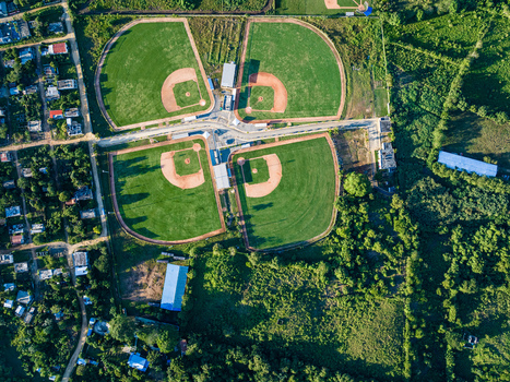 Aerial view of Quality Baseball Academy with four baseball diamonds surrounded by lush greenery and local infrastructure in San Antonio de Guerra Santo Domingo Provinc Dominican Republic. Aerial view of Quality Baseball Academy with four baseball diamonds surrounded by lush greenery and local infrastructure in San Antonio de Guerra Santo Domingo Provinc Dominican Republic.