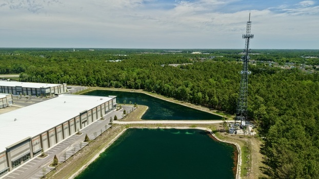 Aerial view of a large industrial warehouse and a telecommunications tower beside retention ponds and a lush forest in World Golf Village Florida United States. Aerial view of a large industrial warehouse and a telecommunications tower beside retention ponds and a lush forest in World Golf Village Florida United States.