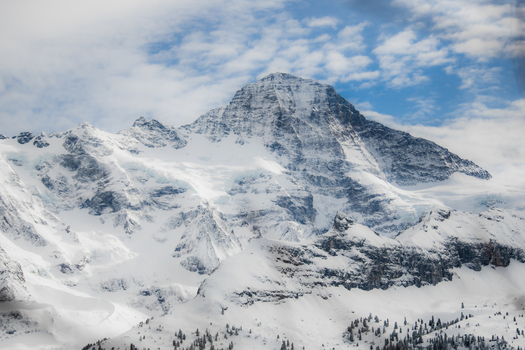View of snow capped mountain peaks pierce the sky their icy faces reflecting the soft light contrasting against the blue sky Murren Switzerland. View of snow capped mountain peaks pierce the sky their icy faces reflecting the soft light contrasting against the blue sky Murren Switzerland.
