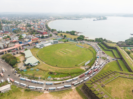 Aerial view of the Galle International Stadium and historic fort walls with buses parked along the road and the bay in the distance Galle Southern Province Sri Lanka. Aerial view of the Galle International Stadium and historic fort walls with buses parked along the road and the bay in the distance Galle Southern Province Sri Lanka.