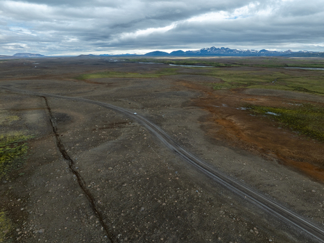 Aerial view of the volcanic landscape of Kerlingarfjoll with a winding road cutting through desolate terrain mossy patches and distant mountains in Hrunamannahreppur Iceland. Aerial view of the volcanic landscape of Kerlingarfjoll with a winding road cutting through desolate terrain mossy patches and distant mountains in Hrunamannahreppur Iceland.