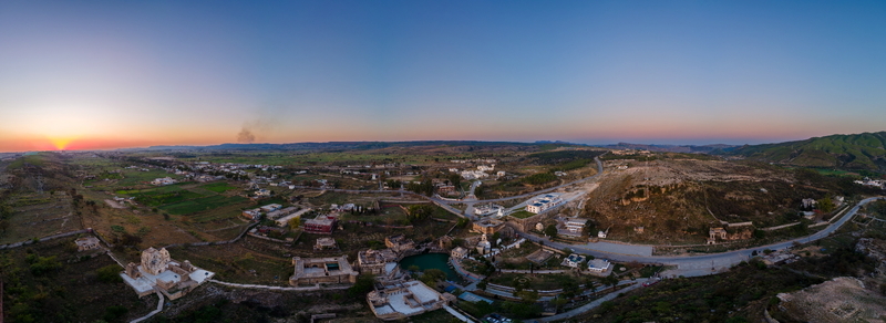 Aerial view of Katas Raj Temple Complex featuring ancient stone structures a sacred pond and surrounding rural landscape under a golden sunset sky in Katas Punjab Pakistan. Aerial view of Katas Raj Temple Complex featuring ancient stone structures a sacred pond and surrounding rural landscape under a golden sunset sky in Katas Punjab Pakistan.