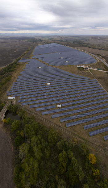 Aerial view of a large solar farm with rows of photovoltaic panels set in a rural landscape under a cloudy sky in Bulgaria. Aerial view of a large solar farm with rows of photovoltaic panels set in a rural landscape under a cloudy sky in Bulgaria.