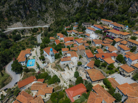 Aerial view of traditional stone houses with red tiled roofs and a white church with a blue dome in the village of Dhermi Vlore County Albania. Aerial view of traditional stone houses with red tiled roofs and a white church with a blue dome in the village of Dhermi Vlore County Albania.