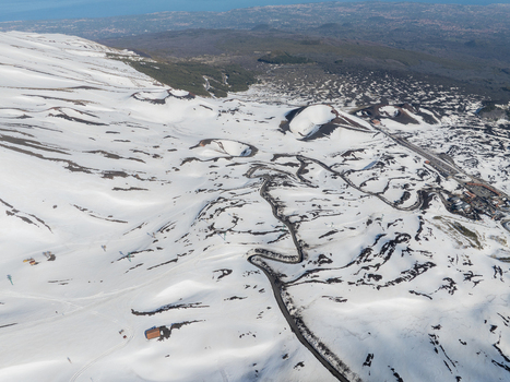 Aerial view of Versante sud dell Etna with snow covered volcanic craters and winding mountain roads in Nicolosi Sicilia Italy. Aerial view of Versante sud dell Etna with snow covered volcanic craters and winding mountain roads in Nicolosi Sicilia Italy.