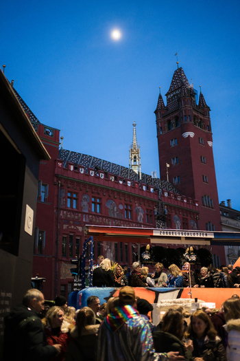 Basel Switzerland 10 March 2025 View of the Rathaus bathed in evening light its red facade contrasting with the twilight sky above a bustling crowd. Basel Switzerland 10 March 2025 View of the Rathaus bathed in evening light its red facade contrasting with the twilight sky above a bustling crowd.
