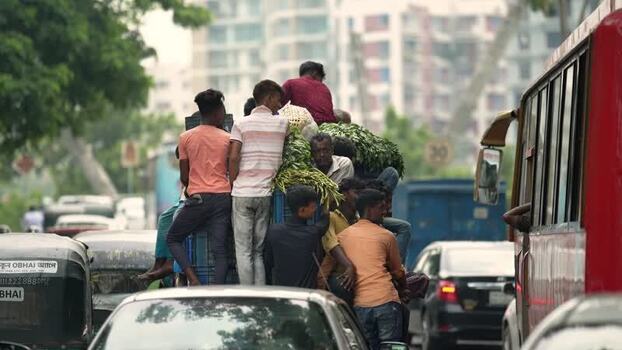 View of people sitting on top of a vehicle in traffic in Bangladesh.