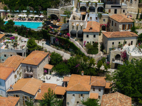 Aerial view of stone buildings with terracotta roofs a turquoise swimming pool and lush Mediterranean greenery at a luxury resort in Dhermi Vlore County Albania. Aerial view of stone buildings with terracotta roofs a turquoise swimming pool and lush Mediterranean greenery at a luxury resort in Dhermi Vlore County Albania.