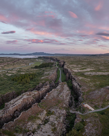Aerial view of the tectonic rift valley at Thingvellir National Park with rugged rock formations walking paths and mossy terrain under a soft sunset sky in Selfoss Blaskogabyggd Iceland. Aerial view of the tectonic rift valley at Thingvellir National Park with rugged rock formations walking paths and mossy terrain under a soft sunset sky in Selfoss Blaskogabyggd Iceland.