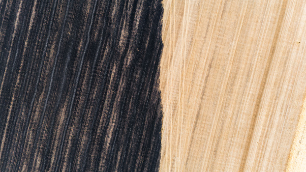 Aerial view of contrasting dark ploughed soil and light golden harvested fields with visible tractor tracks in Sremska Mitrovica Vojvodina Serbia.