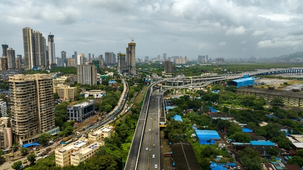 Aerial view of the Atal Bihari Vajpayee Sewri Nhava Sheva Atal Setu bridge spanning across the landscape with urban high rise buildings and lush greenery in Mumbai Maharashtra India. Aerial view of the Atal Bihari Vajpayee Sewri Nhava Sheva Atal Setu bridge spanning across the landscape with urban high rise buildings and lush greenery in Mumbai Maharashtra India.