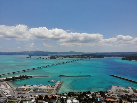 Aerial view of Kouri Bridge stretching across the turquoise waters of the East China Sea towards Yagaji Island under a clear blue sky in Nakijin Okinawa Japan. Aerial view of Kouri Bridge stretching across the turquoise waters of the East China Sea towards Yagaji Island under a clear blue sky in Nakijin Okinawa Japan.