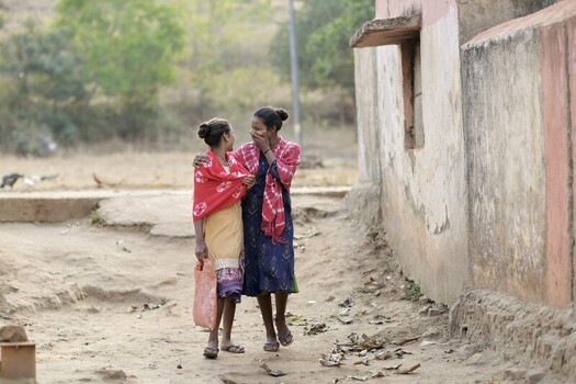 Odisha India 26 March 2026 View of two girls sharing a lighthearted moment by a weathered wall their vibrant clothing contrasting with the earthy tones of the ground. Odisha India 26 March 2026 View of two girls sharing a lighthearted moment by a weathered wall their vibrant clothing contrasting with the earthy tones of the ground.