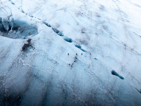 Aerial view of Breidamerkurjokull glacier with hikers walking across the blue ice and deep crevasses in Sveitarfelagid Hornafjordur Iceland. Aerial view of Breidamerkurjokull glacier with hikers walking across the blue ice and deep crevasses in Sveitarfelagid Hornafjordur Iceland.