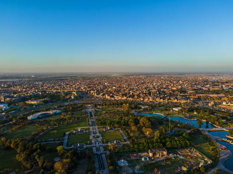 Aerial view of Minar e Pakistan surrounded by lush green gardens and water features in Greater Iqbal Park with the urban landscape of Lahore Lahore Punjab Pakistan.