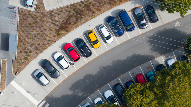 Aerial view of a parking lot with various colorful cars parked in designated spaces surrounded by trees and paved walkways in Liederbach am Taunus Hessen Germany.