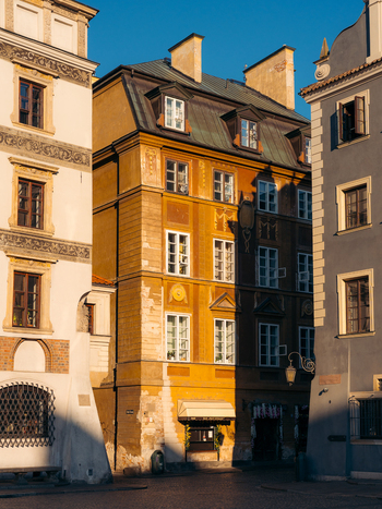 View of Warsaw Old Town featuring historic colorful buildings with ornate facades and windows under warm sunlight in Warsaw Masovian Voivodeship Poland. View of Warsaw Old Town featuring historic colorful buildings with ornate facades and windows under warm sunlight in Warsaw Masovian Voivodeship Poland.
