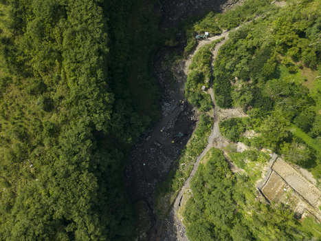 Aerial view of Tambang Pasir Merapi Kali Gendol Sand Mine with excavators and trucks in the riverbed surrounded by forest Kecamatan Cangkringan Daerah Istimewa Yogya Indonesia. Aerial view of Tambang Pasir Merapi Kali Gendol Sand Mine with excavators and trucks in the riverbed surrounded by forest Kecamatan Cangkringan Daerah Istimewa Yogya Indonesia.