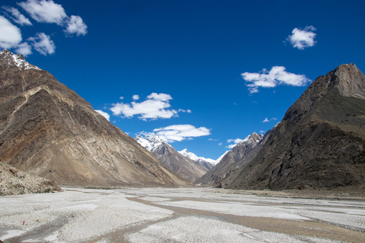 View of K2 Base Camp surrounded by rugged Karakoram mountains and a wide rocky riverbed under a clear blue sky in Ghakhar Gilgit Pakistan. View of K2 Base Camp surrounded by rugged Karakoram mountains and a wide rocky riverbed under a clear blue sky in Ghakhar Gilgit Pakistan.