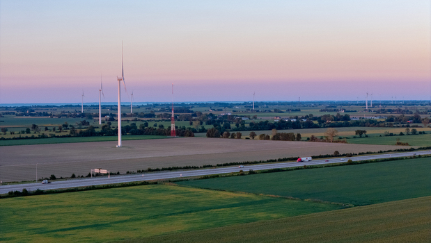 Aerial view of wind turbines standing in agricultural fields near a highway at sunset in Lakeshore Ontario Canada. Aerial view of wind turbines standing in agricultural fields near a highway at sunset in Lakeshore Ontario Canada.