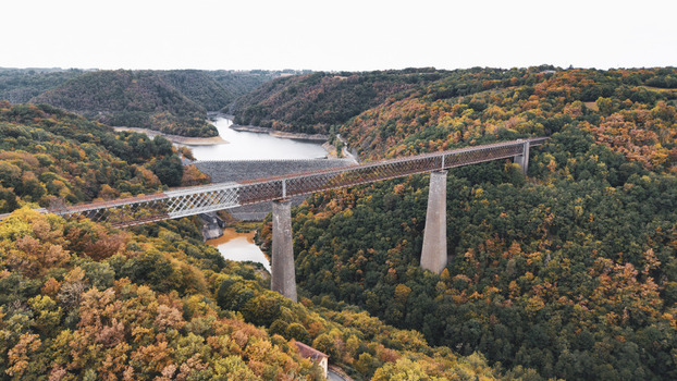 Aerial view of the historic Fades viaduct spanning a river valley surrounded by dense autumn forest in Les Ancizes Comps Auvergne Rhone Alpes France. Aerial view of the historic Fades viaduct spanning a river valley surrounded by dense autumn forest in Les Ancizes Comps Auvergne Rhone Alpes France.