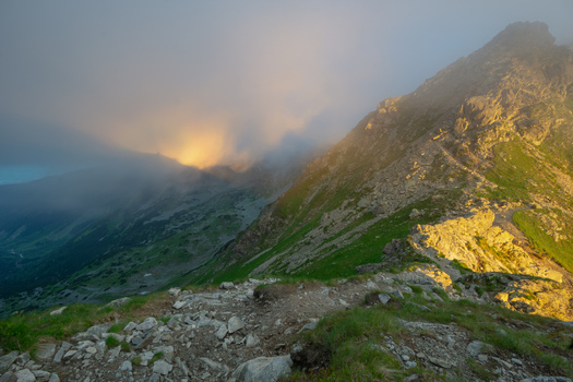 View of Smutne sedlo in Western Tatras with golden sunlight illuminating the rocky ridge and thick fog rolling over the green mountain slopes Ziar Zilina Region Slovakia. View of Smutne sedlo in Western Tatras with golden sunlight illuminating the rocky ridge and thick fog rolling over the green mountain slopes Ziar Zilina Region Slovakia.