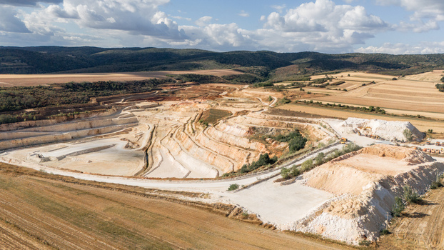 Aerial view of the open pit mine showing terraced limestone extraction levels piles of white stone and surrounding agricultural fields in Besenovo Vojvodina Serbia. Aerial view of the open pit mine showing terraced limestone extraction levels piles of white stone and surrounding agricultural fields in Besenovo Vojvodina Serbia.