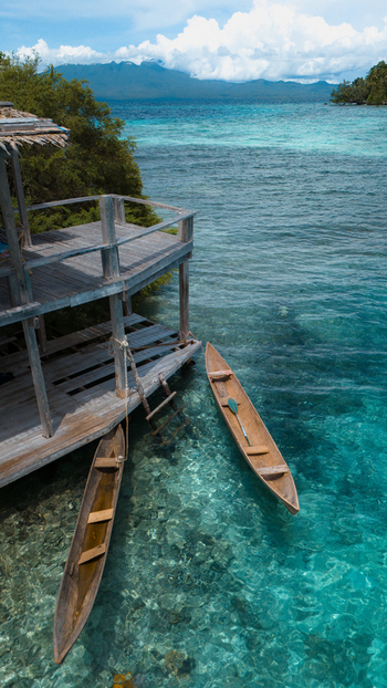 Aerial view of crystal clear turquoise waters meet wooden stilts and traditional canoes a tranquil island paradise beckons from the depths Gizo Western Province Solomon Islands. Aerial view of crystal clear turquoise waters meet wooden stilts and traditional canoes a tranquil island paradise beckons from the depths Gizo Western Province Solomon Islands.
