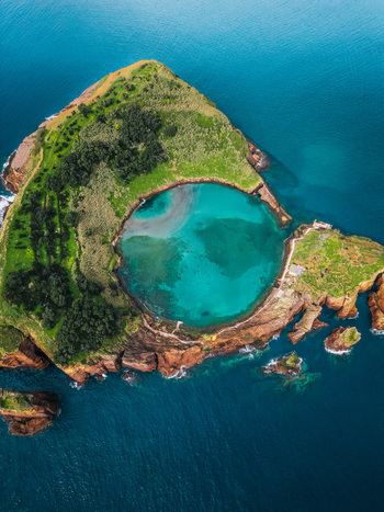 Aerial view of Vila Franca Islet displaying a captivating turquoise lagoon embraced by verdant slopes and rugged volcanic rock Vila Franca do Campo Azores Portugal.