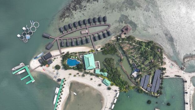 Aerial view of Pulau Lima Resort featuring overwater bungalows arranged in a fish shape a swimming pool sandy beaches and boats docked at the pier in Kasemen Banten Indonesia. Aerial view of Pulau Lima Resort featuring overwater bungalows arranged in a fish shape a swimming pool sandy beaches and boats docked at the pier in Kasemen Banten Indonesia.