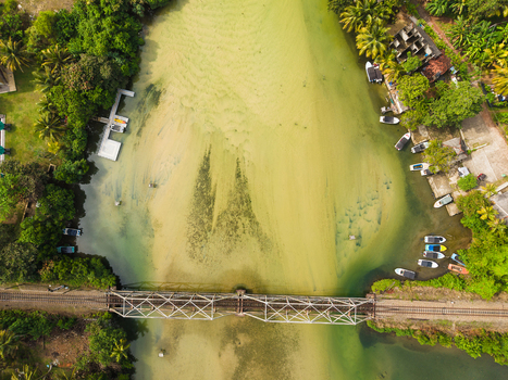 Aerial view of Koggala Lake with a railway bridge crossing the water moored boats and lush tropical vegetation in Koggala Southern Province Sri Lanka. Aerial view of Koggala Lake with a railway bridge crossing the water moored boats and lush tropical vegetation in Koggala Southern Province Sri Lanka.