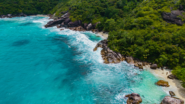 Aerial view of Anse Soleil Beachcomber Hotel featuring turquoise ocean waters granite boulders and lush tropical vegetation along the coastline in Mahe Baie Lazare Seychelles.