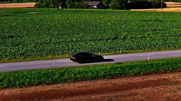 Aerial view of a black car on a rural road Latvia. Aerial view of a black car on a rural road Latvia.