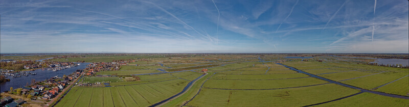 Aerial view of the verdant fields meet the tranquil waters where boats rest in the harbor near Oostknollendam Noord Holland Netherlands. Aerial view of the verdant fields meet the tranquil waters where boats rest in the harbor near Oostknollendam Noord Holland Netherlands.