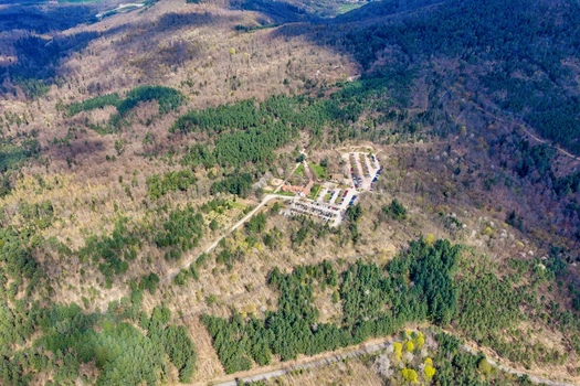 Aerial view of a cluster of buildings nestled amidst a dense forest revealing a stark contrast between the man made structures and the wild untamed landscape Kintzheim Grand Est France.