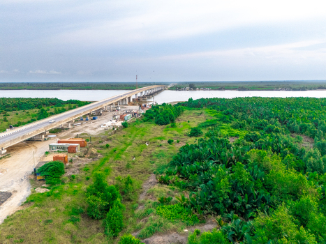 Aerial view of the bridge spanning the river surrounded by lush green vegetation and shipping containers in Bonny Town Rivers Nigeria. Aerial view of the bridge spanning the river surrounded by lush green vegetation and shipping containers in Bonny Town Rivers Nigeria.