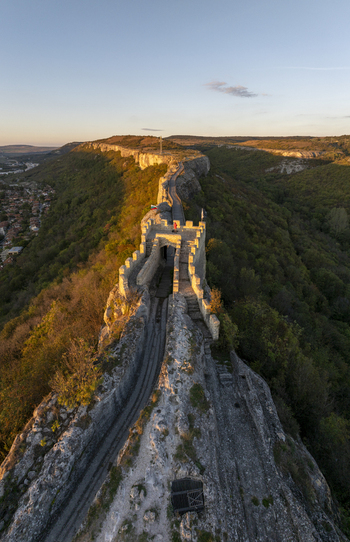 Aerial view of Ovech Fortress a historic stone fortification on a narrow plateau illuminated by golden hour light with surrounding greenery and cliffs in Provadia Varna Bulgaria. Aerial view of Ovech Fortress a historic stone fortification on a narrow plateau illuminated by golden hour light with surrounding greenery and cliffs in Provadia Varna Bulgaria.