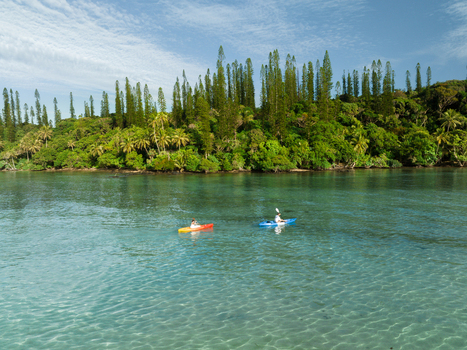 Aerial view of two kayakers glide across the turquoise waters framed by lush emerald green vegetation Goro South Province New Caledonia. Aerial view of two kayakers glide across the turquoise waters framed by lush emerald green vegetation Goro South Province New Caledonia.